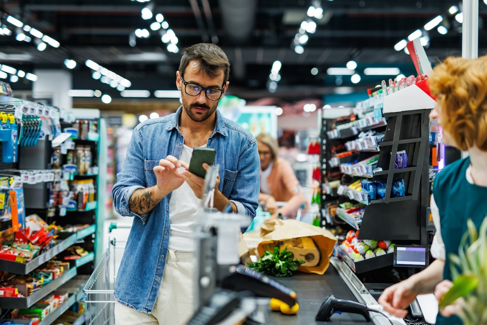 Homem fazendo pagamento na fila do supermercado, que conta com sistema integrado de pagamento.