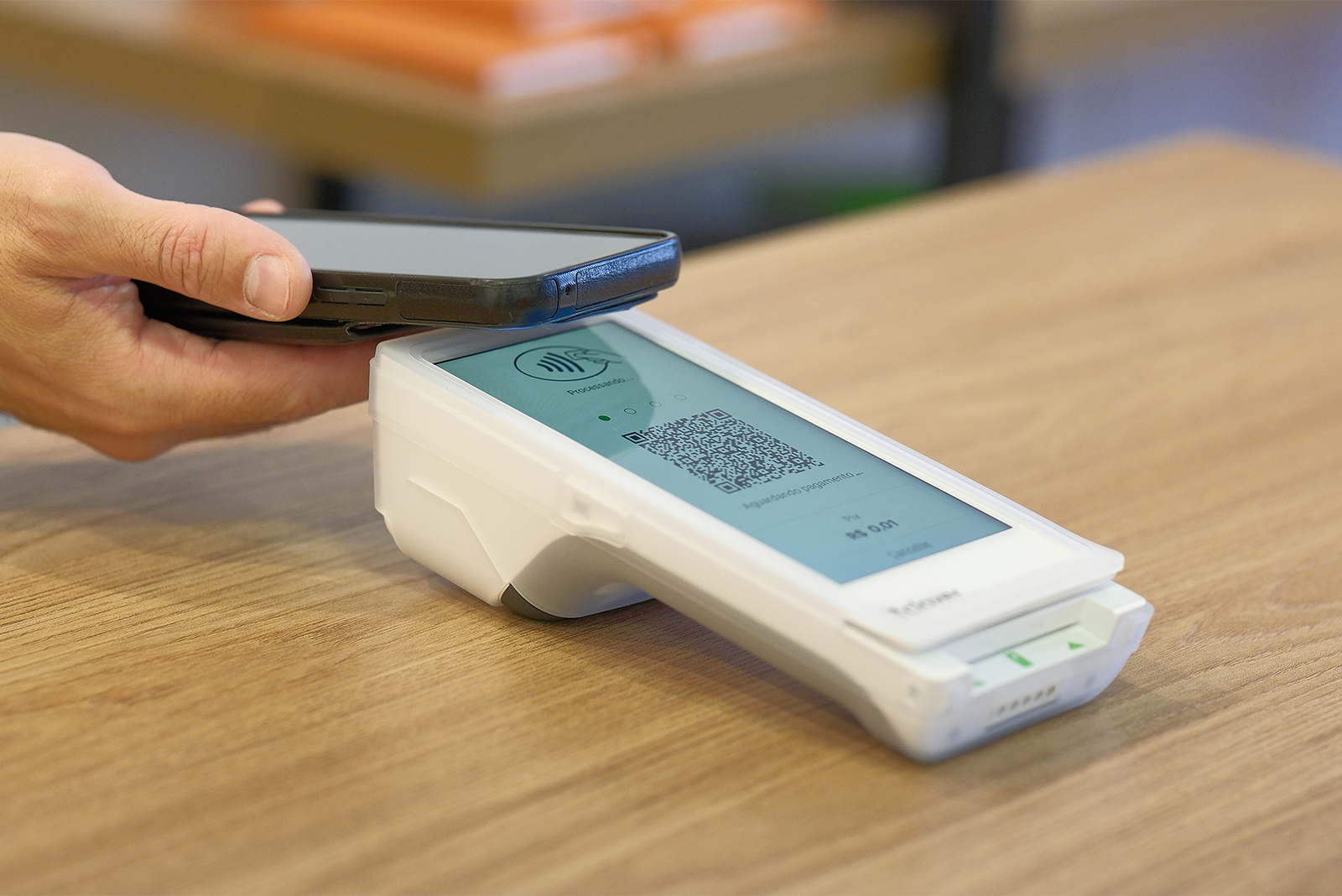 Dispositivo Clover Flex sendo utilizado para fazer pagamento por aproximação com celular,.